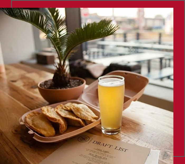 A wooden tray with some food and a glass of beer